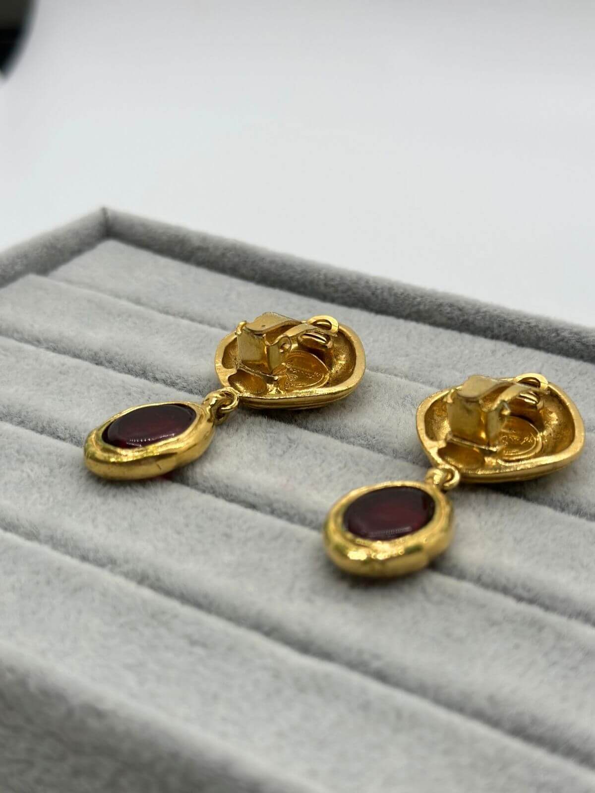 Chanel gold and red Gripoix earring on grey background. Showing side of earrings.