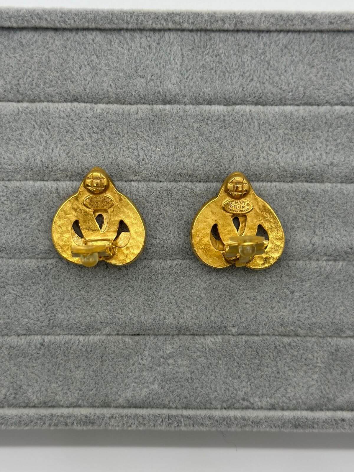 Chanel gold clip on heart earring on grey fixture. Showing signature on back.