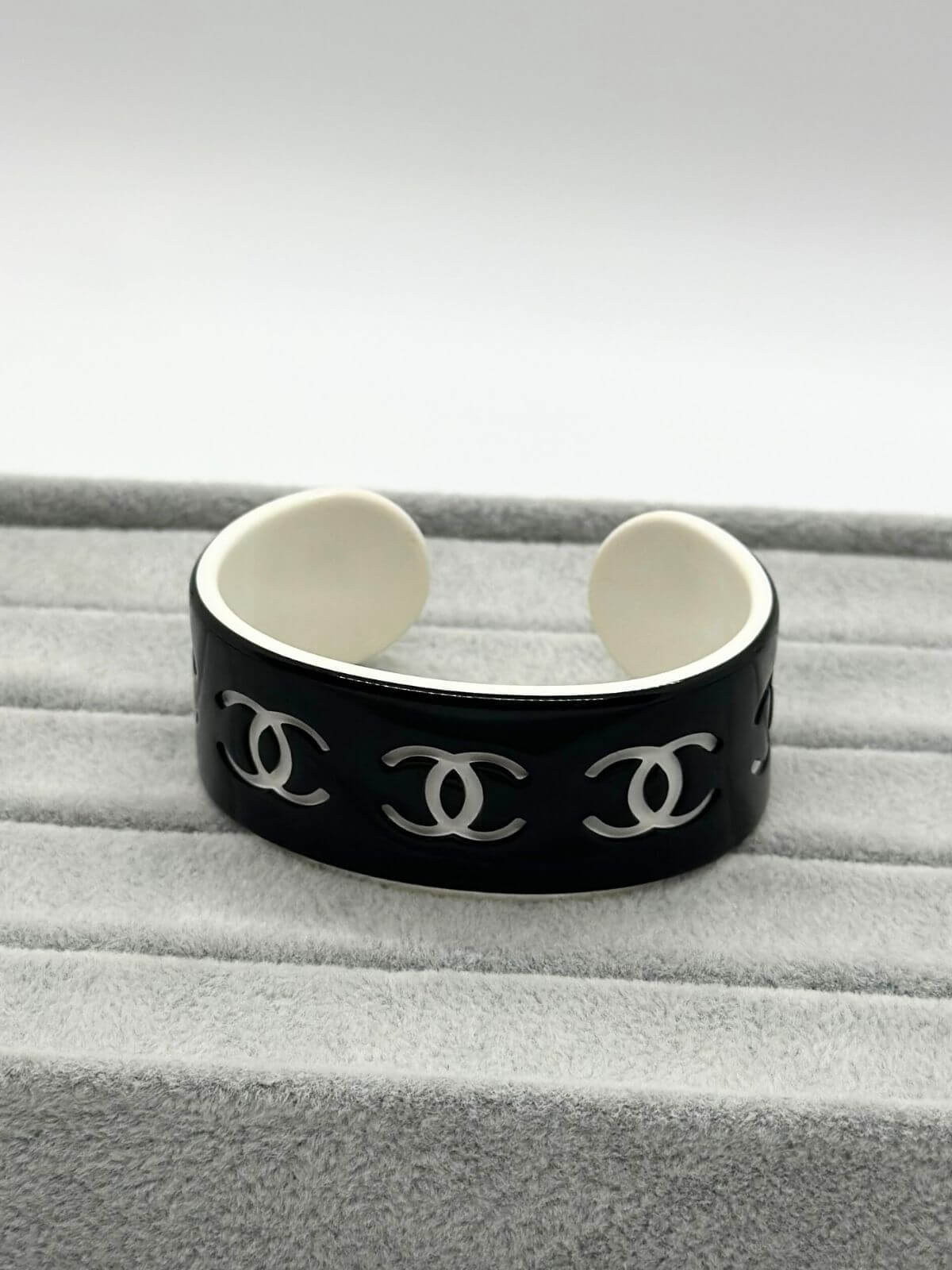 Chanel black and white resin CC cuff on grey background.