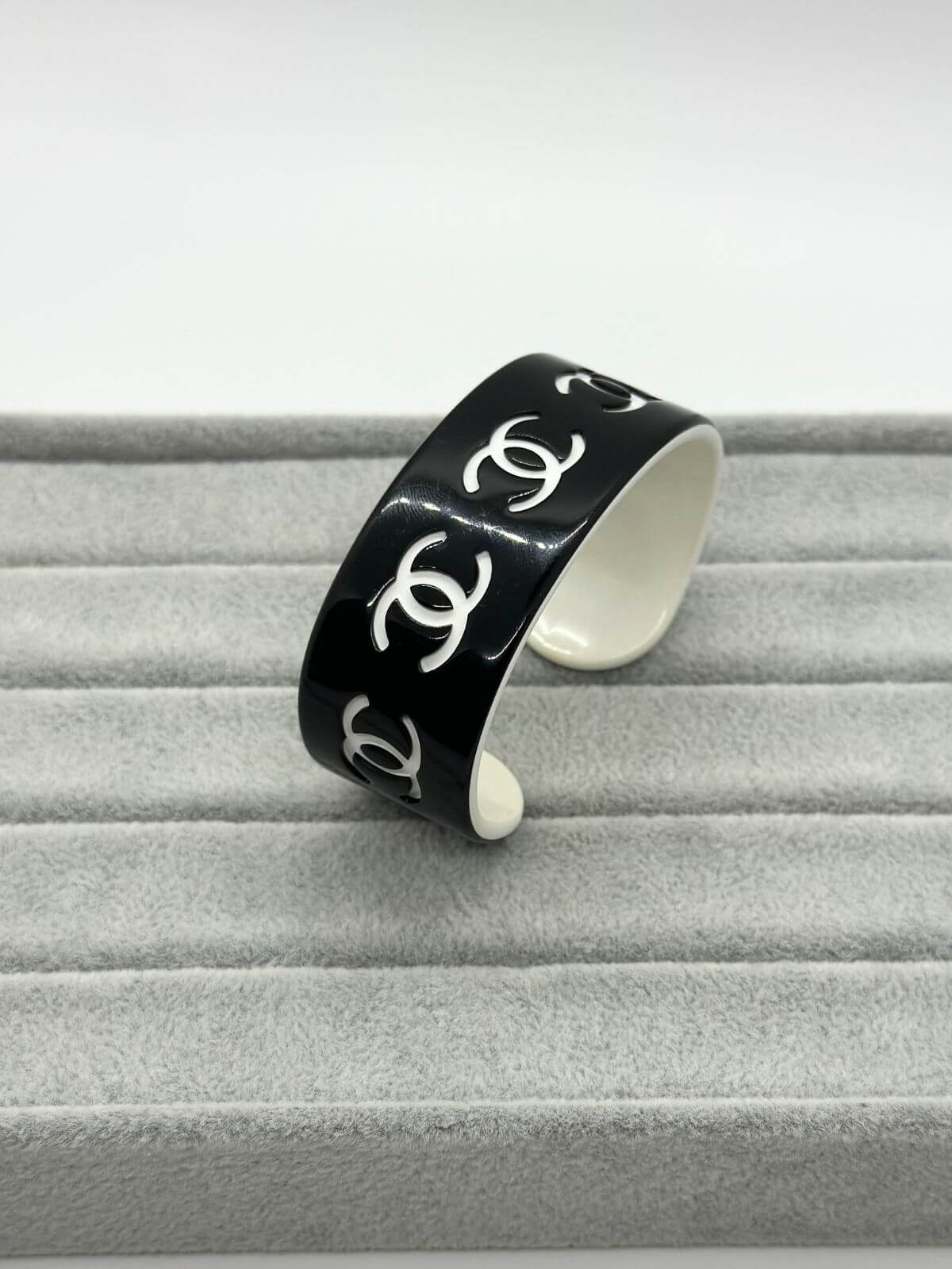 Chanel black and white resin CC cuff on grey background.