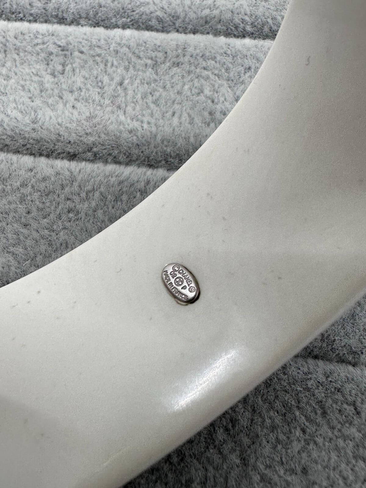 Chanel black and white resin CC cuff on grey background. Signature.