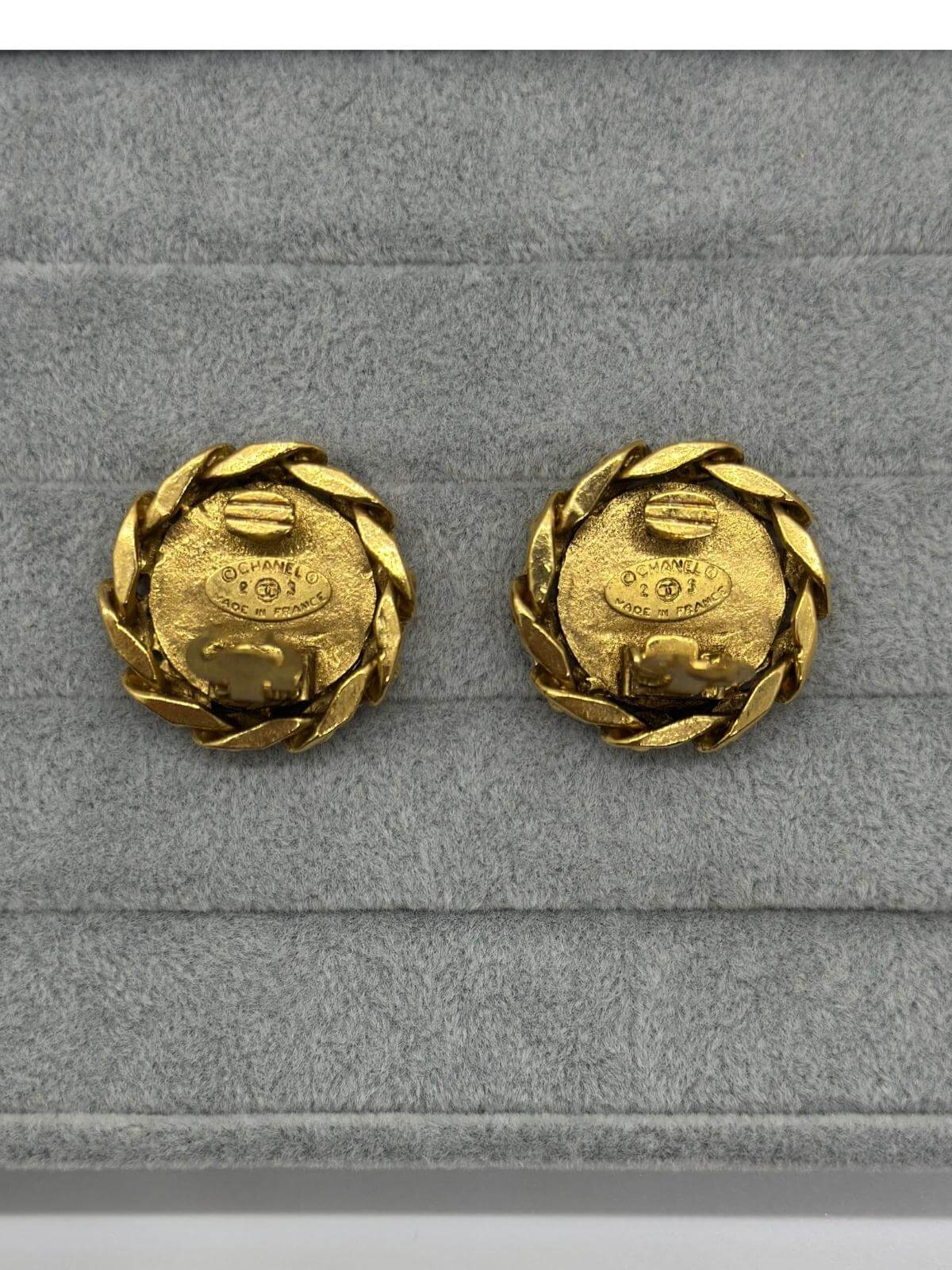 Chanel gold round clip on earring with crystal on grey and white background. Showing signature on back side. 