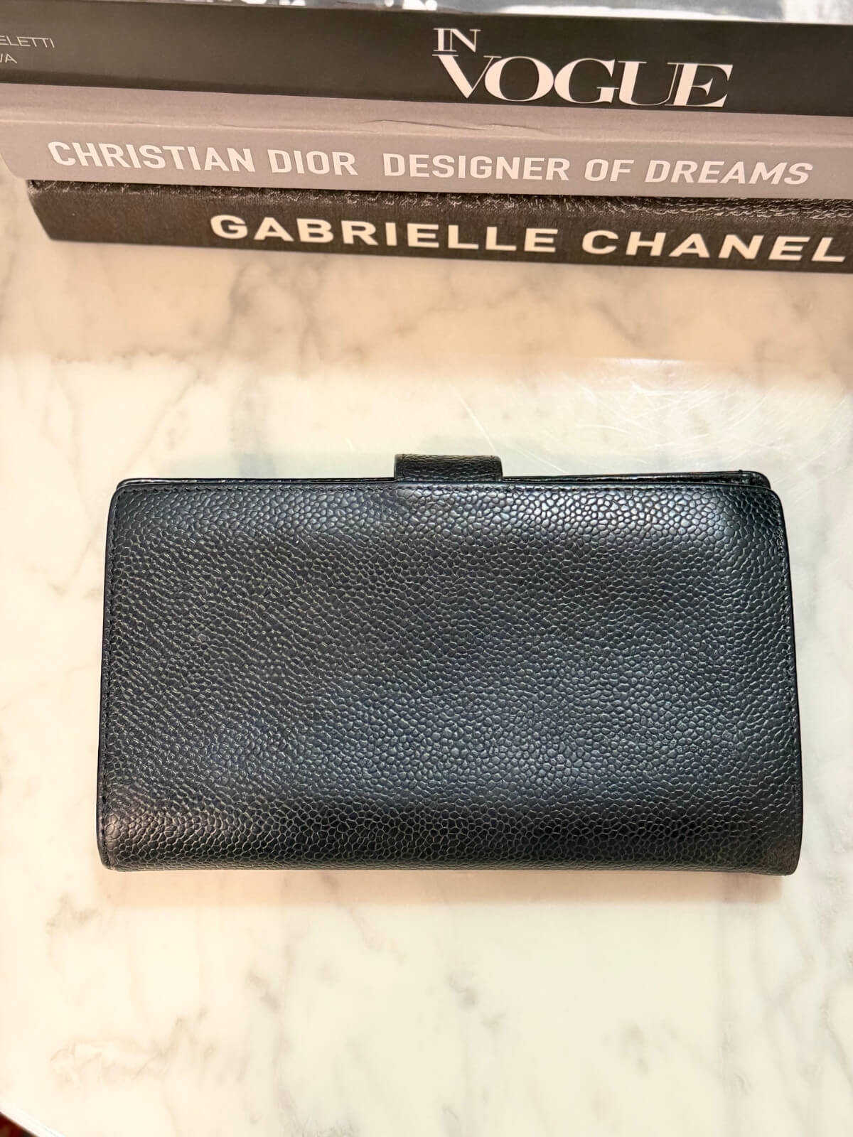 Louise Row featuring vintage Chanel black cavier embossed wallet on table 