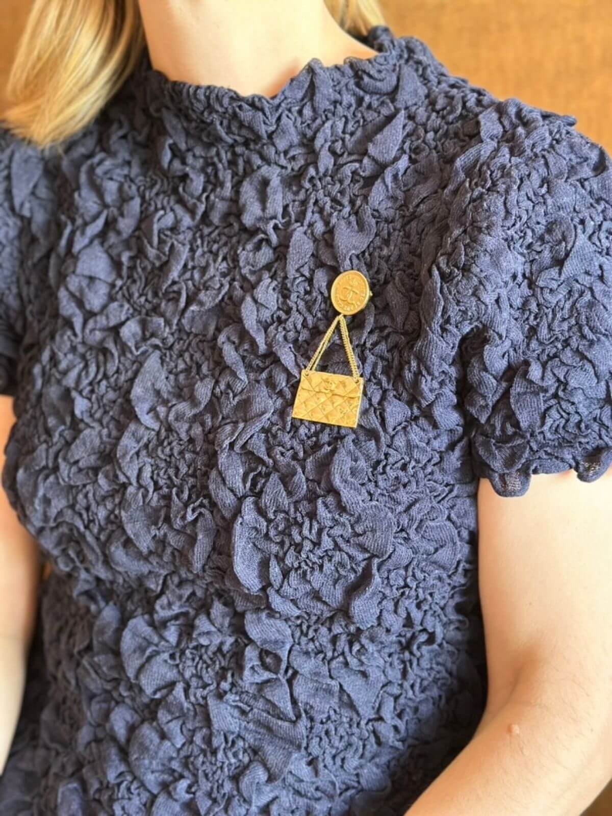 Navy lace dress with a gold brooch worn by a person