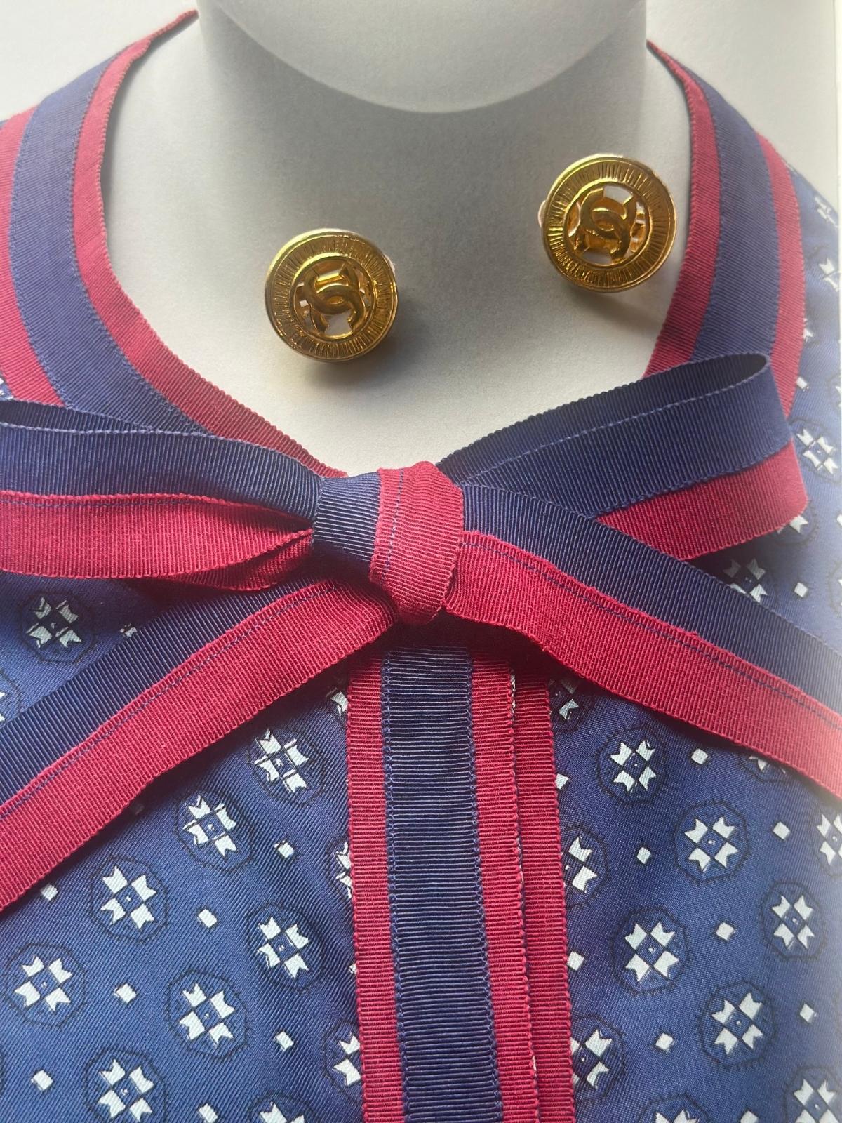 Mannequin wearing a blue dress with red ribbon and gold button Chanel vintage earrings.