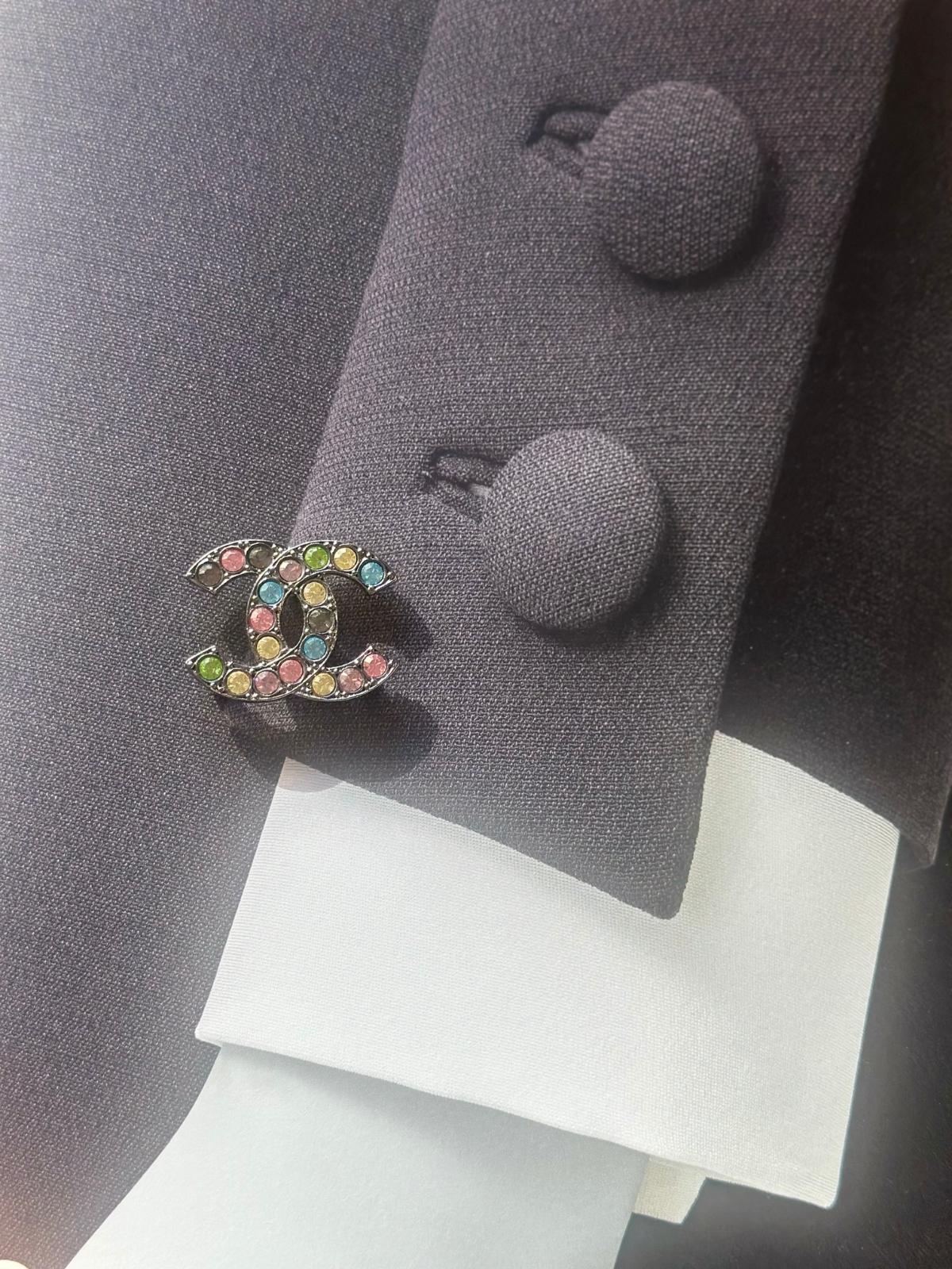 Multicolored Chanel brooch on a gray coat with buttons