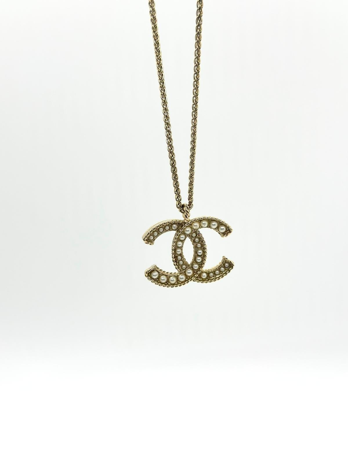 Chanel gold and pearl necklace on white background.