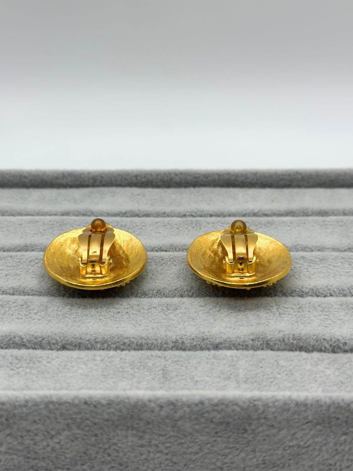 Back of Vintage Chanel gold round earring with CC logo in center on grey background. Showing clip