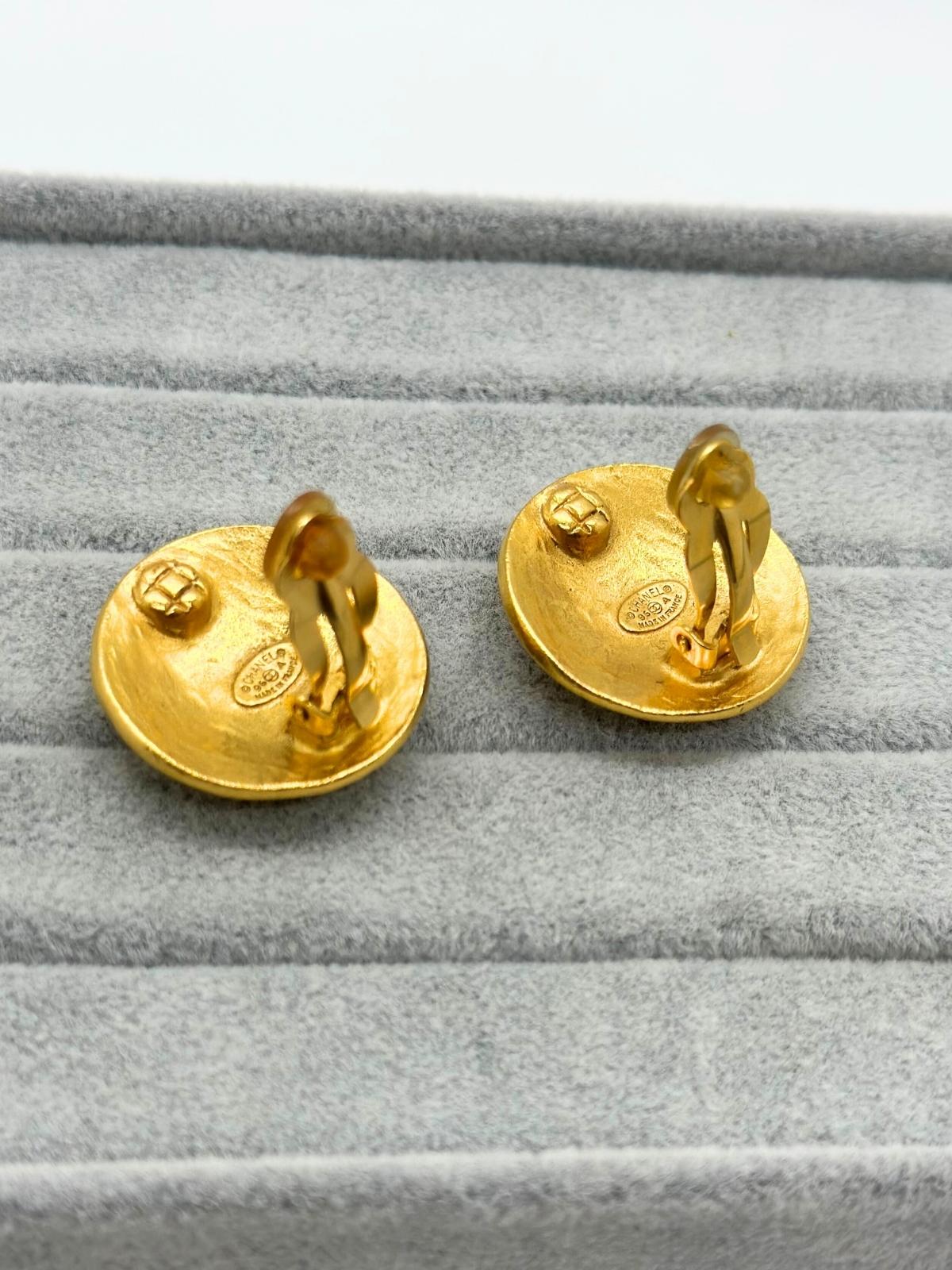 Back of Vintage Chanel gold round earring with CC logo in center on grey background. Showing clip and signature.