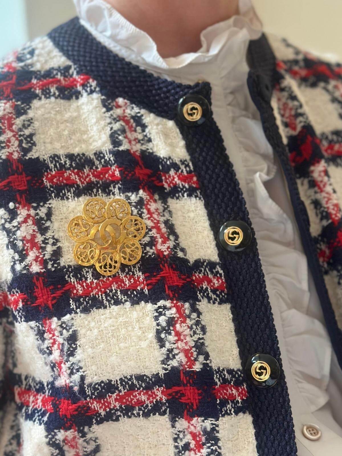 Model in quilted jacket wearing Chanel gold flower brooch, close up.