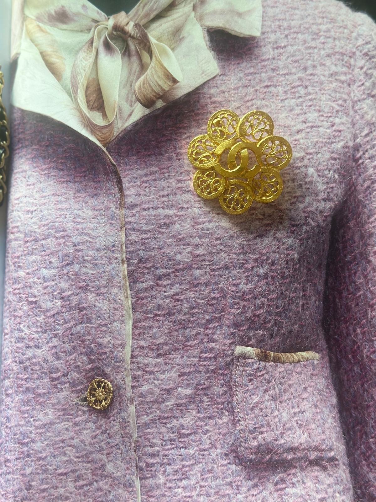 Close-up of a purple textured fabric with a Chanel spheres gold brooch.