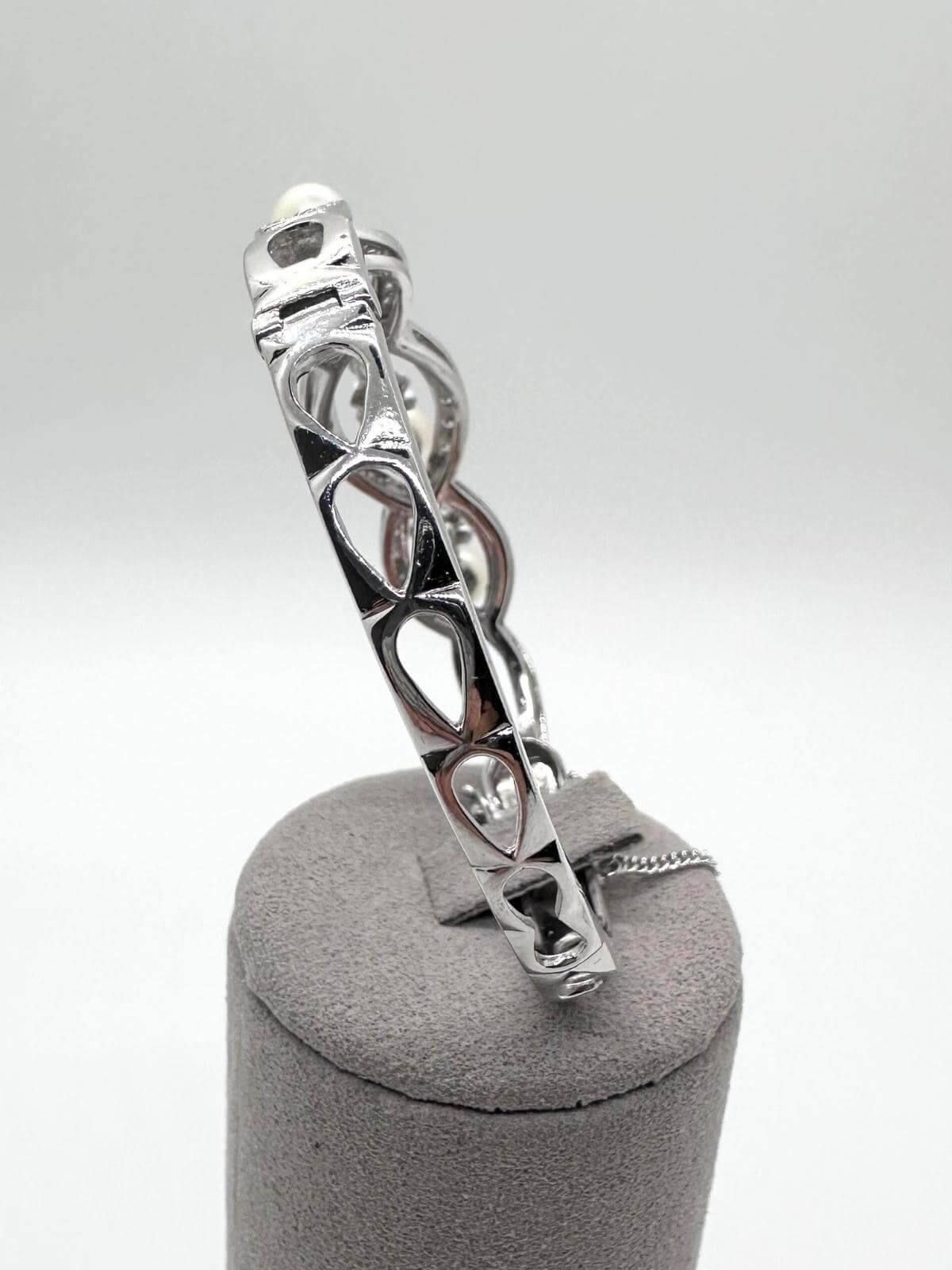  Side angle White gold and pearl bracelet on white background on grey fixture