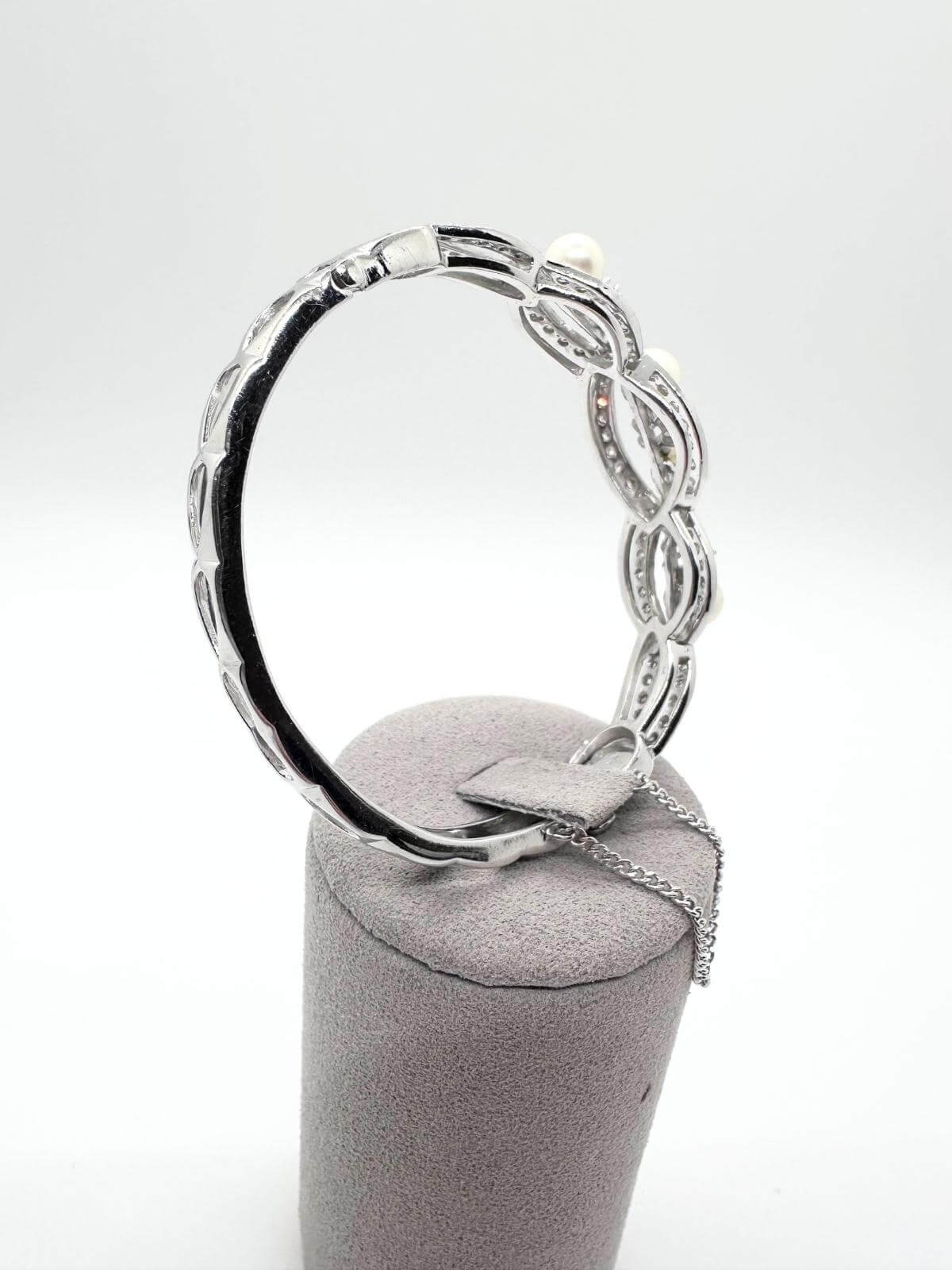  Side angle White gold and pearl bracelet on white background on grey fixture